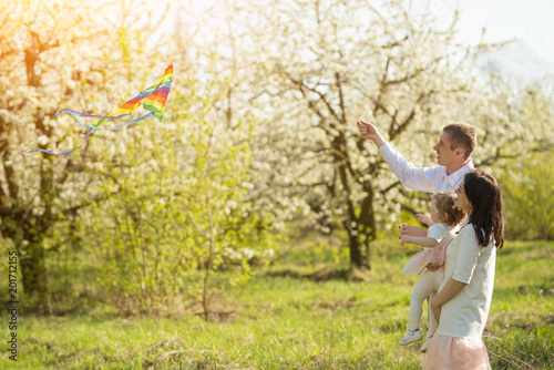 Happy family with a kite in the spring gardens