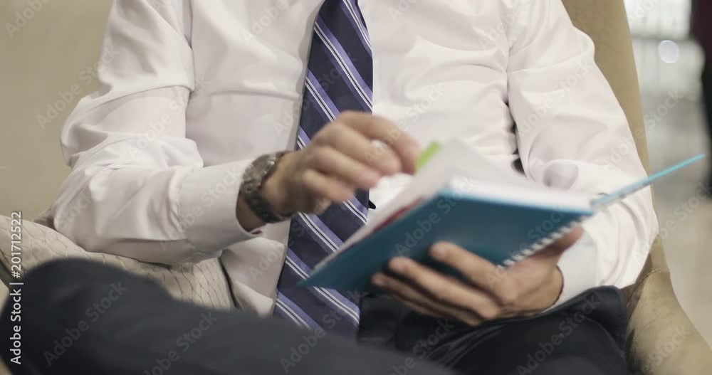 A businessman reads a notepad sitting in the hotel lobby or office. A businessman reads a notepad sitting in the hotel lobby or office.