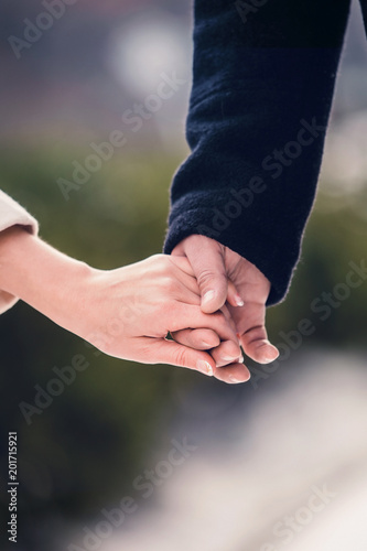 a man in a black coat holds a girl's hand on a date