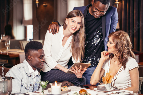 Two mixed couples having a good time at restaurant talking about future vacations photo