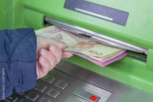 Photo of hand taking from ATM Ukrainian hryvnas