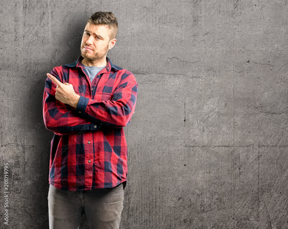 Young handsome man pointing away side with finger Young handsome man pointing away side with finger