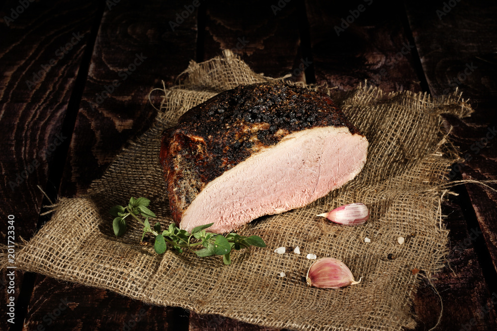 Fototapeta premium Schab wędzony. Tradycyjnie wędzone wędliny w kompozycja na lnianym obrusie z ziołami