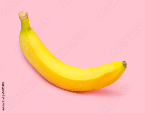 One yellow banana on a pink background