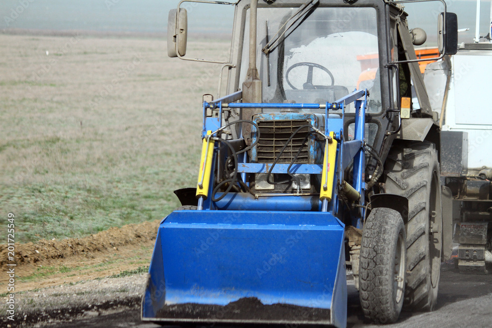 Countryside asphalt road reconstruction. wheel bulldozer with blade working. Countryside asphalt road reconstruction. wheel bulldozer with blade working.