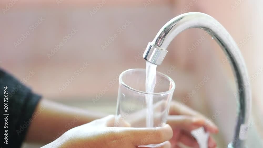woman hands pouring water from faucet in glass