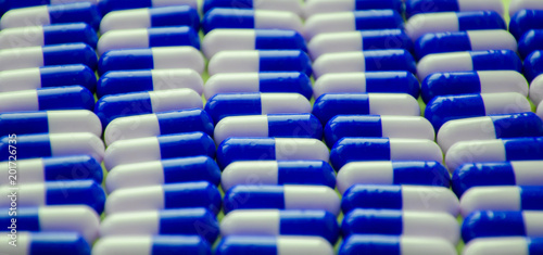 blue and white pills or capsules lies in a rows on blue background close up wallpaper concept design