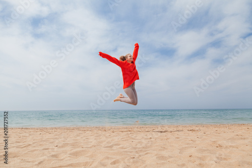 girl jumping on a sandy beach sea shore photo