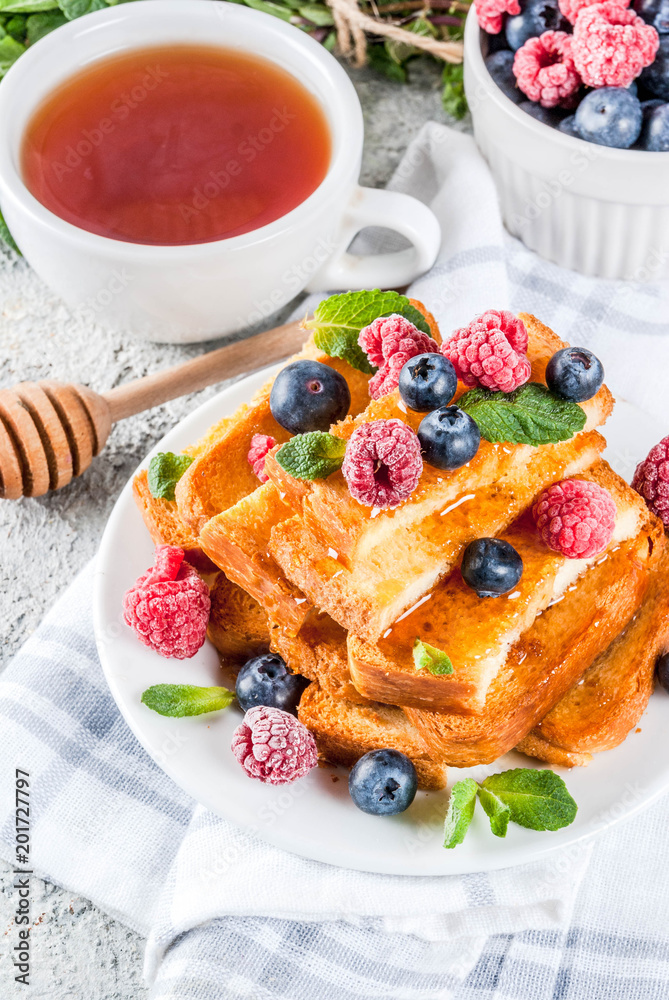 Healthy summer breakfast, baked french toasted bread sticks with fresh berry and honey, morning light grey stone background copy space Healthy summer breakfast, baked french toasted bread sticks with fresh berry and honey, morning light grey stone background copy space