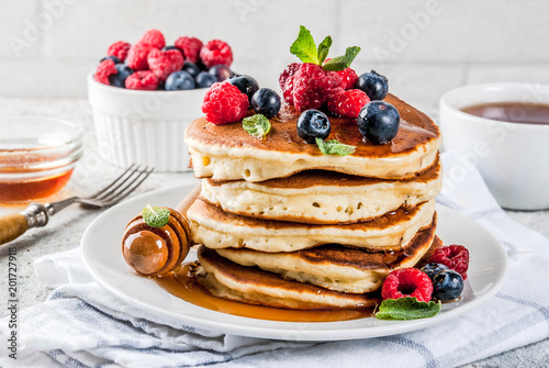 Healthy summer breakfast,homemade classic american pancakes with fresh berry and honey, morning light grey stone background copy space