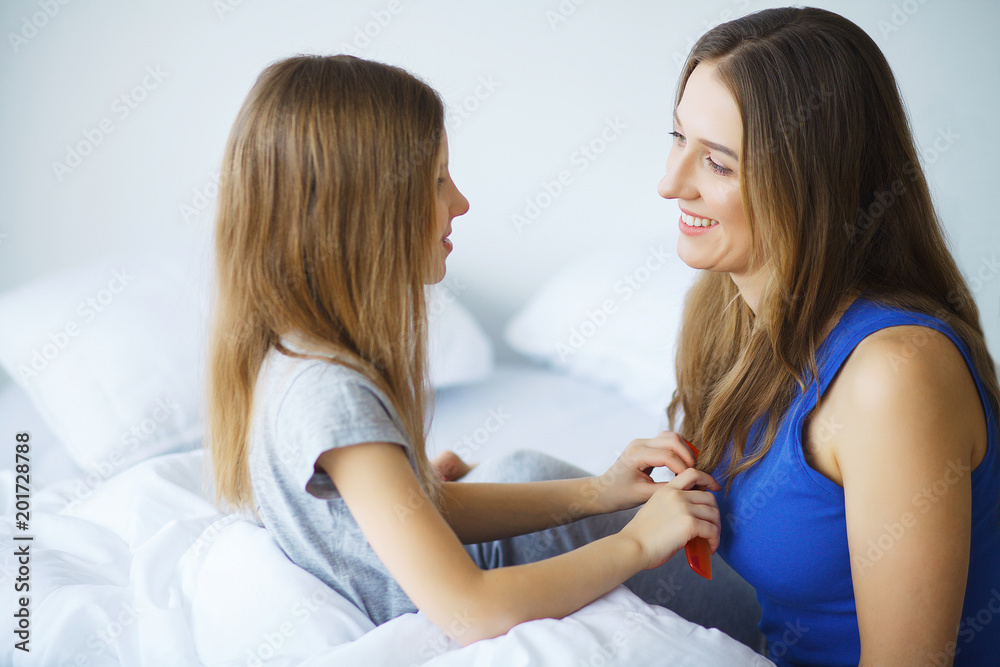 Woman and young girl lying in bed smiling Woman and young girl lying in bed smiling