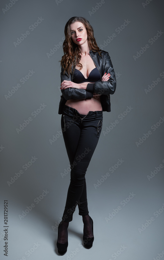 Studio fashion shot: portrait of attractive young woman in pants, bra and leather jacket. Full length Studio fashion shot: portrait of attractive young woman in pants, bra and leather jacket. Full length
