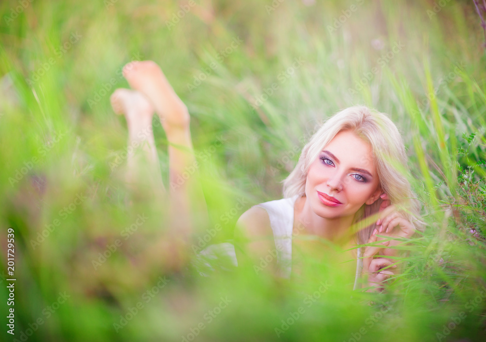 Smiling beautiful young woman resting among green grass Smiling beautiful young woman resting among green grass
