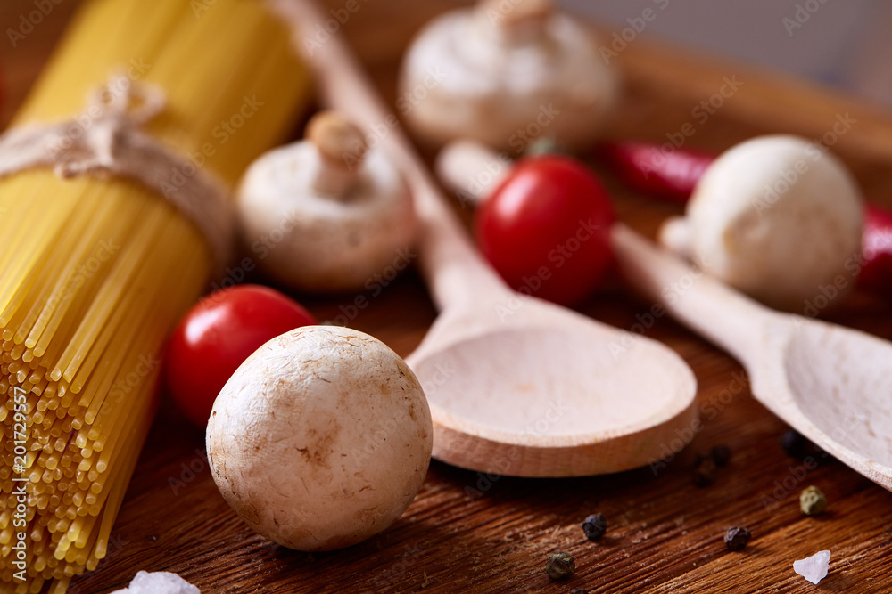 Uncooked pasta, tomatoes and spice on wooden background, top view, close-up, selective focus Uncooked pasta, tomatoes and spice on wooden background, top view, close-up, selective focus
