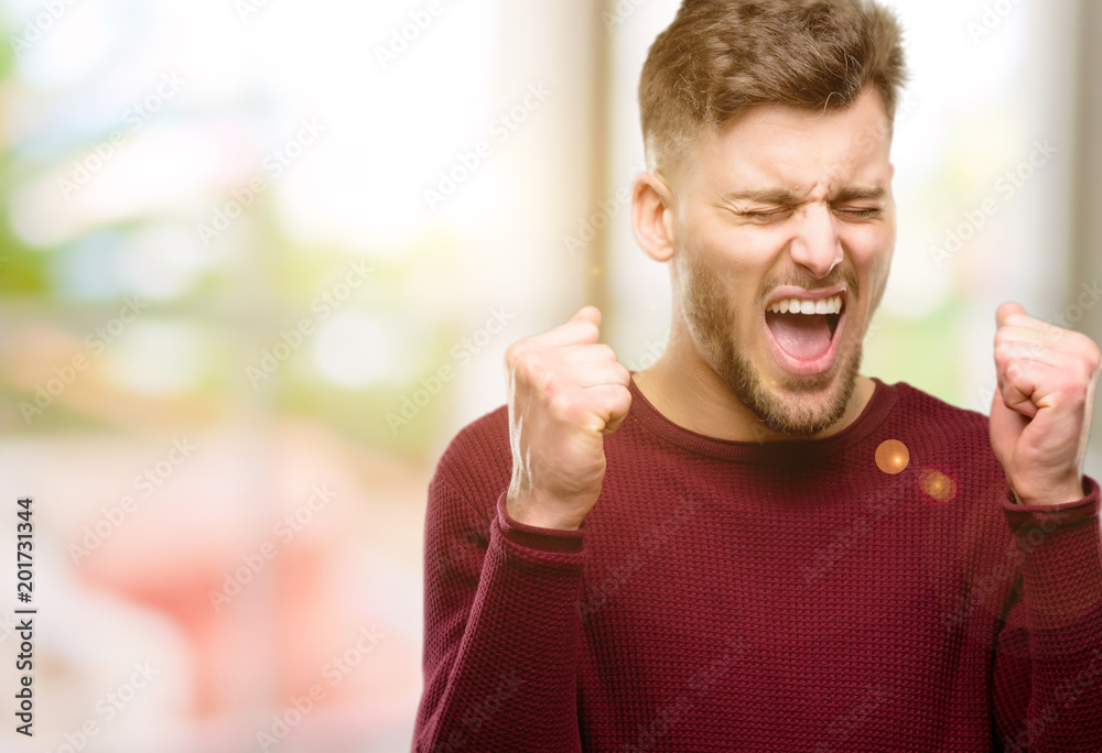 Handsome young man happy and excited expressing winning gesture. Successful and celebrating victory, triumphant Handsome young man happy and excited expressing winning gesture. Successful and celebrating victory, triumphant