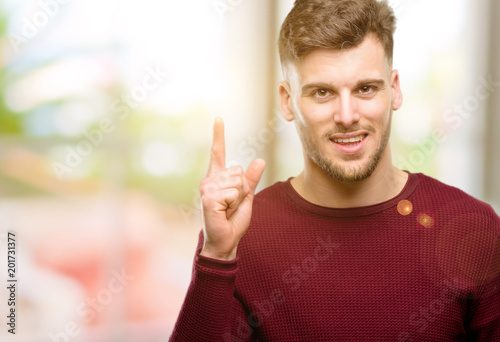Handsome young man happy and surprised cheering expressing wow gesture pointing up