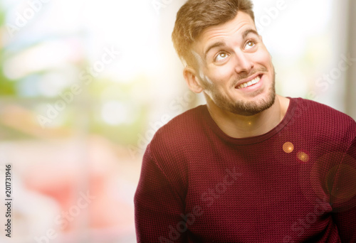 Handsome young man confident and happy with a big natural smile laughing looking up