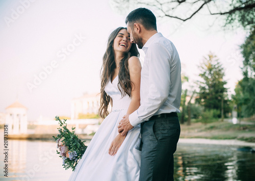 Newlyweds emotionaly laught at the walk near pond. Outdoors