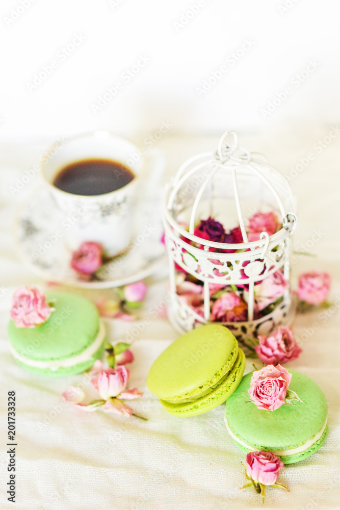 Dessert: A Delicate Fresh Colorful French Macaroons In Pastel Colors With Flowers Roses On A Light Textile Background, Top View Dessert: A Delicate Fresh Colorful French Macaroons In Pastel Colors With Flowers Roses On A Light Textile Background, Top View