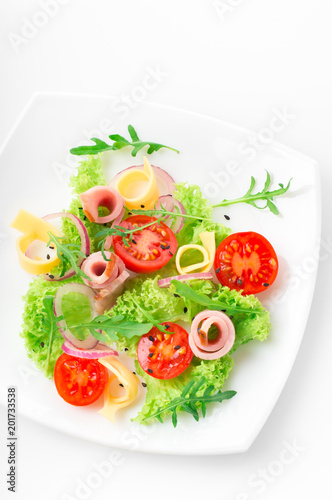 Fresh salad with tomatoes, arugula, cheese and ham on the white plate and white background