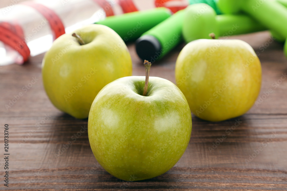 Green apples with skipping rope and dumbbels on brown wooden table Green apples with skipping rope and dumbbels on brown wooden table