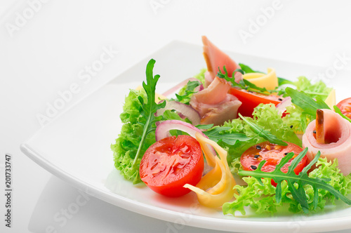 Fresh salad with tomatoes, arugula, cheese and ham on the white plate and white background