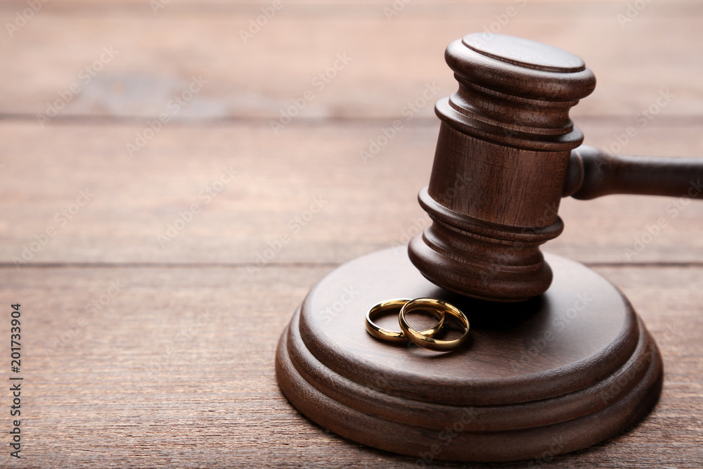 Judge gavel with wedding rings on wooden table
