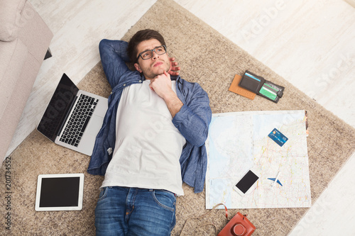 Man dreaming about travel, lying on floor