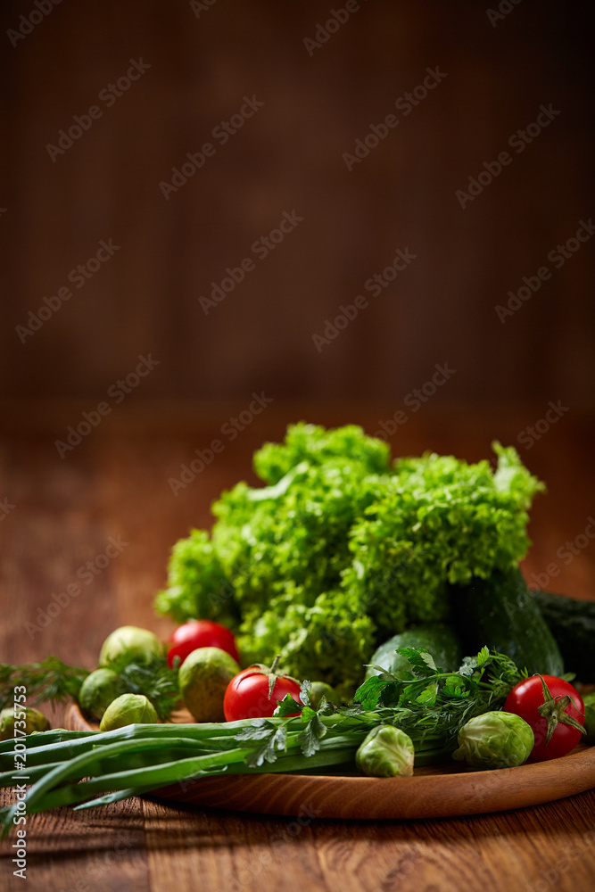 Vegetarian still life of fresh vegetables on wooden plate over rustic background, close-up, flat lay. Vegetarian still life of fresh vegetables on wooden plate over rustic background, close-up, flat lay.
