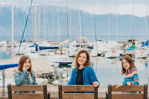 Outdoor portrait of happy mother and two young teenage girls resting by the lake. Image taken in Lausanne, Switzerland © annanahabed