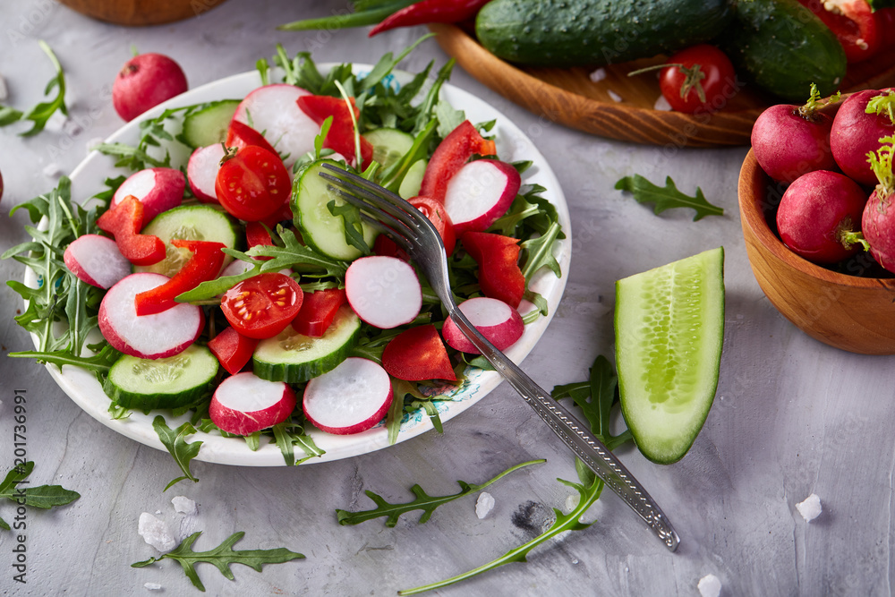 Wooden plate with vegetables for a vegetarian salad on white textured background, close-up, selective focus Wooden plate with vegetables for a vegetarian salad on white textured background, close-up, selective focus
