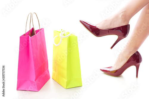 Beautiful woman's legs Put on red high heels and colorful shopping bags.