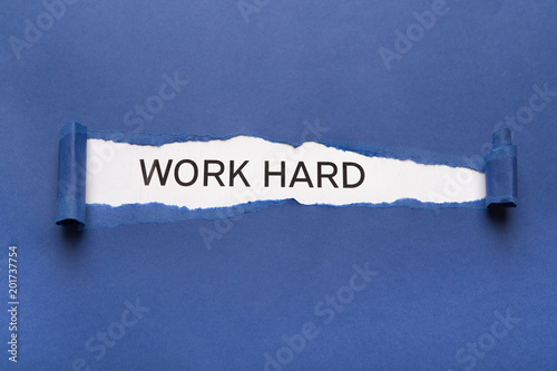 Text Work hard on white background appearing behind torn blue paper