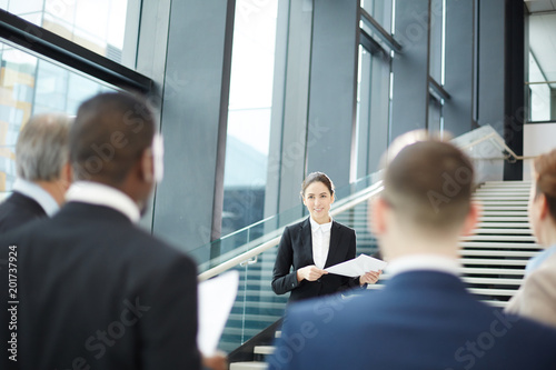 Young businesswoman making report in front of audience at business briefing in airport lounge