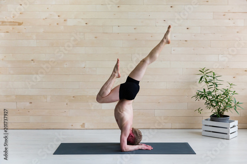 Sporty man practicing yoga.  Head stand, sirsasana exercise photo