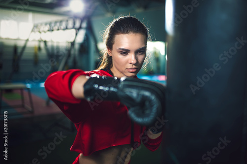 Fit slim young beautiful brunette woman boxing in sportswear. Dark dim light. Toned image © zamuruev