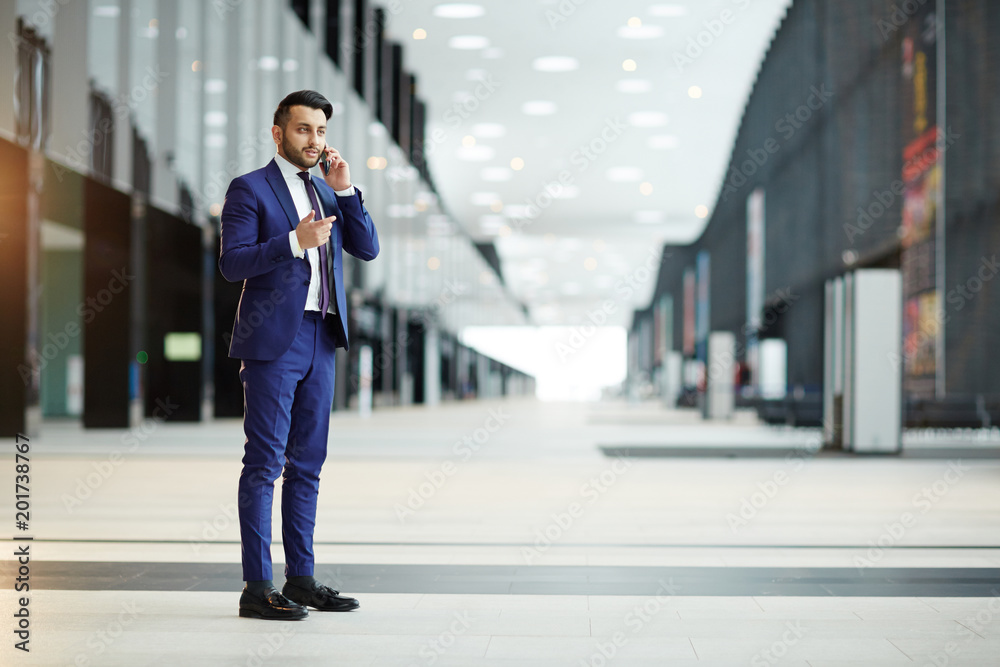 Young elegant agent in suit consulting his client during foreign travel while standing in modern airport Young elegant agent in suit consulting his client during foreign travel while standing in modern airport