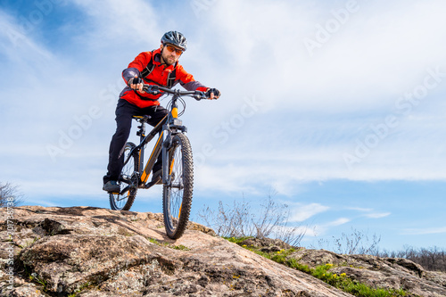 Cyclist in Red Jacket Riding Mountain Bike Down Rocky Hill. Extreme Sport and Adventure Concept. © Maksym Protsenko