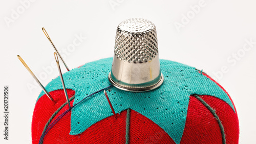 Red and green Pincushion with a thimble on top of it