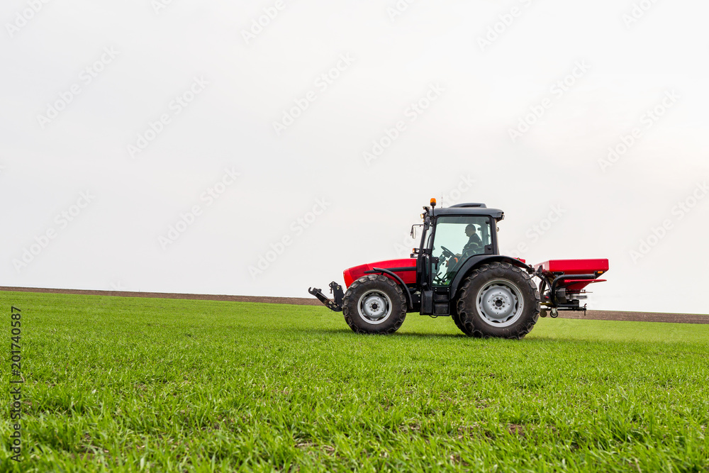 Farmer in tractor fertilizing wheat field at spring with npk Farmer in tractor fertilizing wheat field at spring with npk