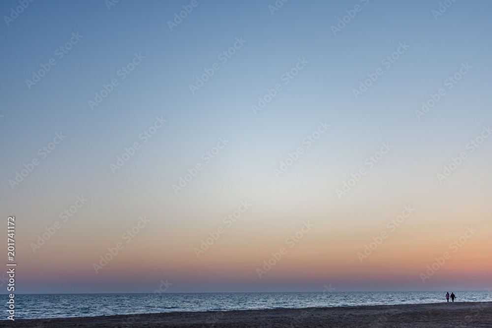 at sunset, a couple of lovers walking along the sea at sunset, a couple of lovers walking along the sea