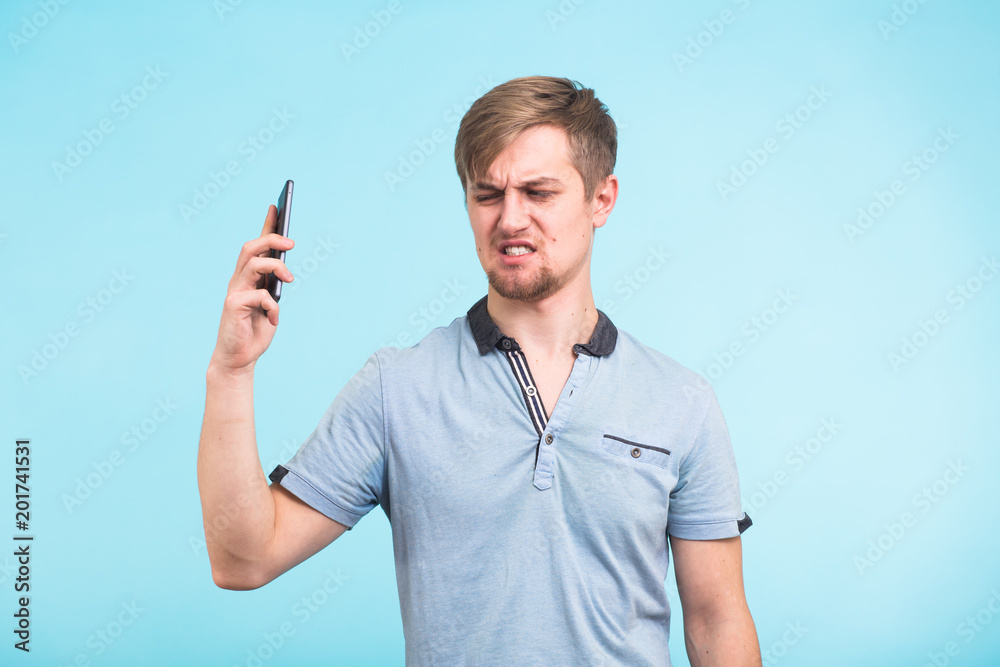 Handsome man with a tired and irritated look takes the phone away from her ear trying to move away from the complaints of an obsessive and annoying people