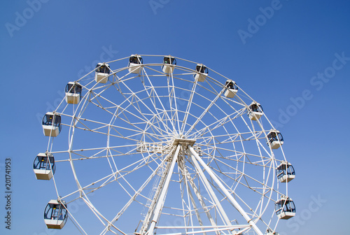 Ferris wheel over blue sky. Carousel. Cubicle. Joy.