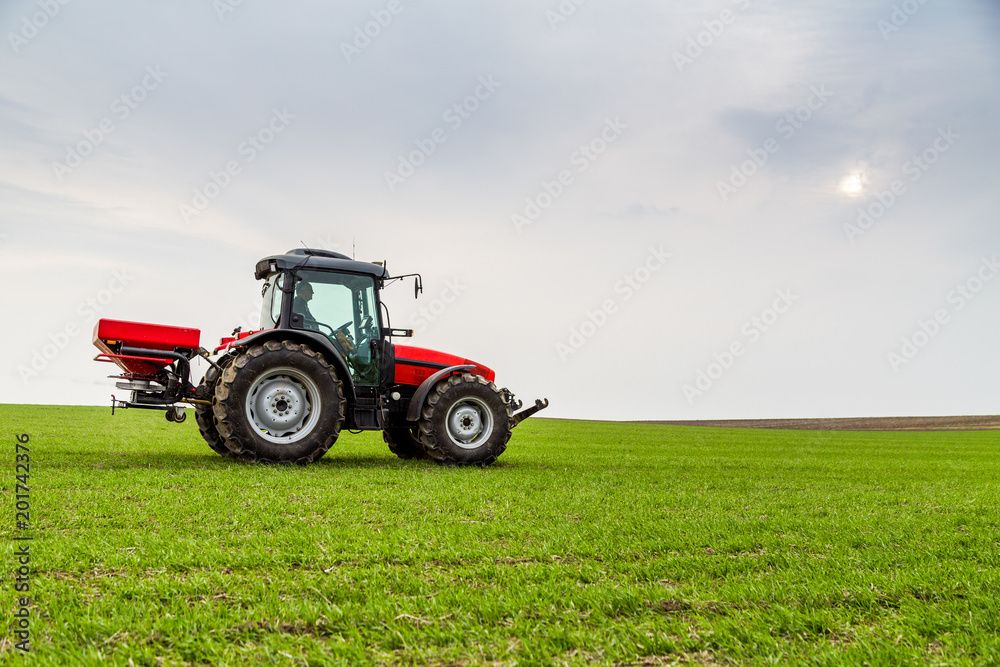 Farmer in tractor fertilizing wheat field at spring with npk Farmer in tractor fertilizing wheat field at spring with npk