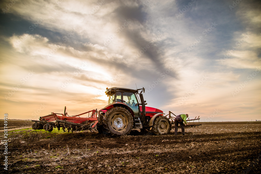 Obraz premium Tractor cultivating field at spring