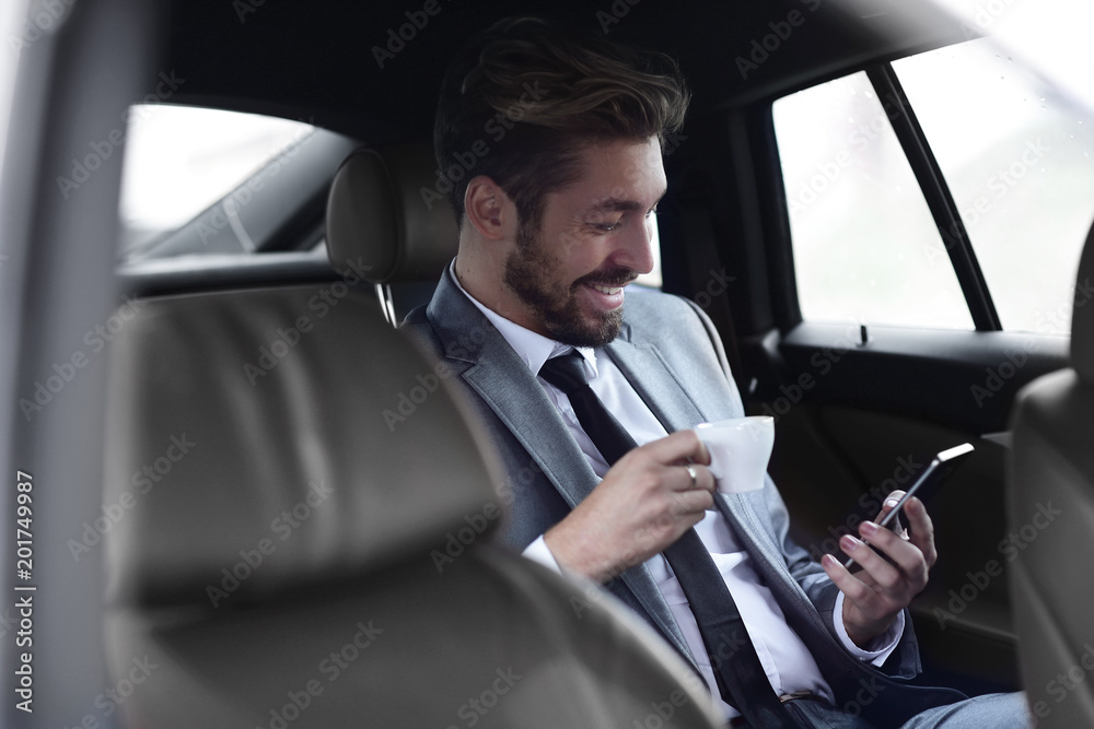 Businessman drinking coffee in car with phone in hand Businessman drinking coffee in car with phone in hand