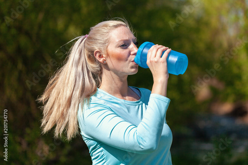 Young woman drinks water in a sport dress