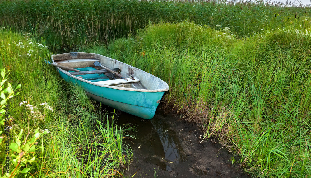 Old green plastic fishing boat at the lake in green grass Old green plastic fishing boat at the lake in green grass