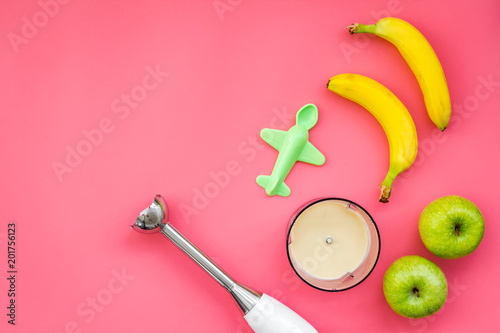 Homemade baby food. Cook puree with apple and banana with immersion blender. Pink background with toy top view space for text