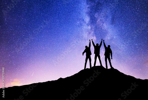 Silhouettes of team on mountain peak. Sport and active life concept on the ni...